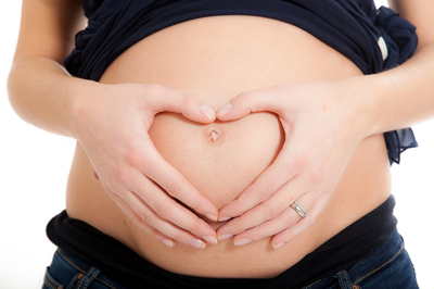 Pregnant woman creating a heart on her belly with her hands