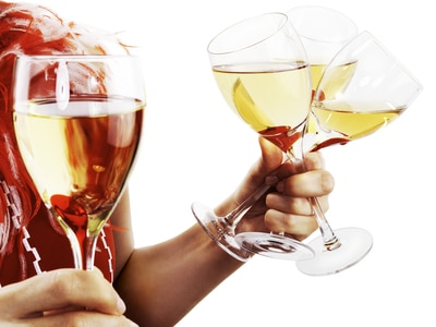 Person holding three glasses of wine in one hand and another in the other hand.