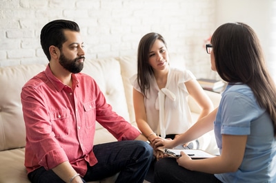 Group of three people sitting in a circle comforting each other.