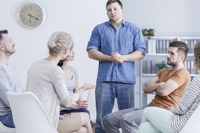 Group of people sitting while listening to a person speaking.