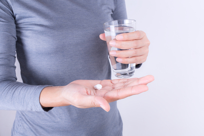 Woman taking a pill with a glass of water.