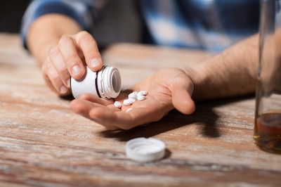 Man with a bottle of pills pouring them into his hand.