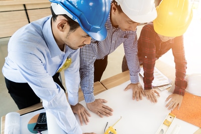 Three workers with hard harts looking at plans.