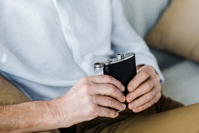Person drinking from a metal flask.