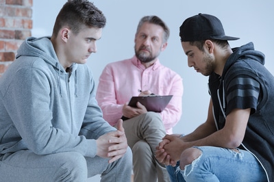 Three men sitting in a group having a discussion.