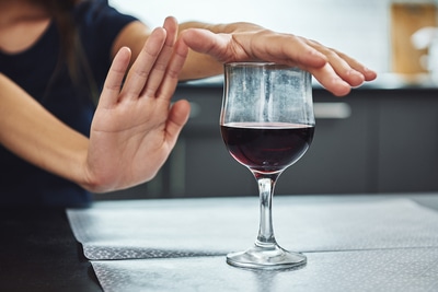 Person refusing a glass of wine.