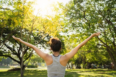 woman outside with her hands raised in triumph.