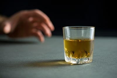 Hand reaching for a glass of liquor.
