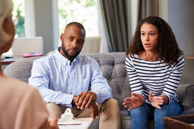 Couple sitting on a couch meeting with a therapist.