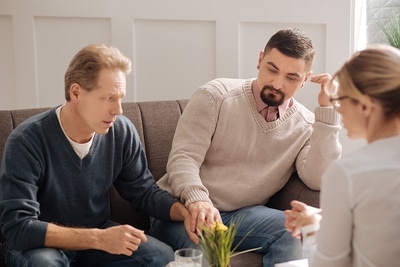 Gay couple meeting with a therapist.
