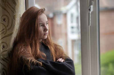 Teen looking out a window in deep thought