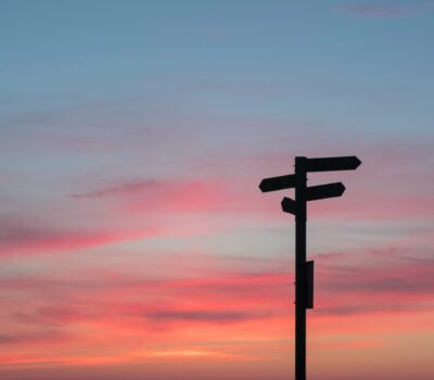 Directional signs against a sunset