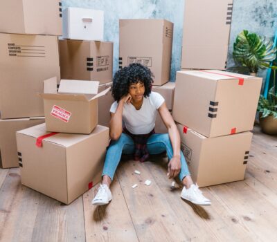 Woman sitting on the floor surrounded by cardboard moving boxes